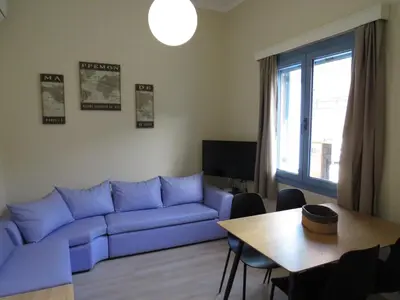 a living room with a blue couch and a table at Cosy apartment in Koum Kapi Beach in Chania Town