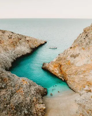a group of people on a beach between two rocks at Stone House by the Sea in Tavronitis