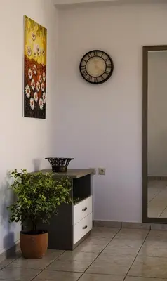a clock on a wall next to a desk with a plant at IKARUS apartment with courtyard & pool in Chania in Stérnai