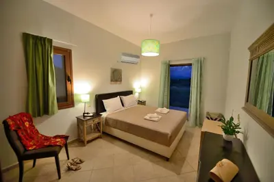 a bedroom with a bed and a chair and a window at Niriides Apartments in Kissamos
