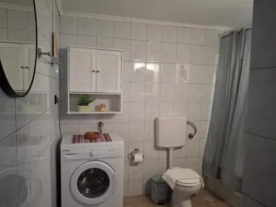 a bathroom with a washing machine and a toilet at Casa Ioanna - Elegant Residence in Kalivianí