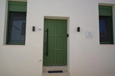 a green door on a white building with two windows at Casa di Keti in Chania Town