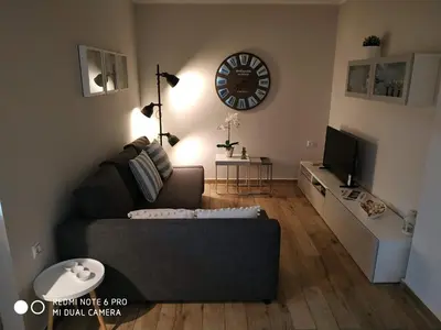 a living room with a couch and a clock on the wall at Evan's place in Chorafakia