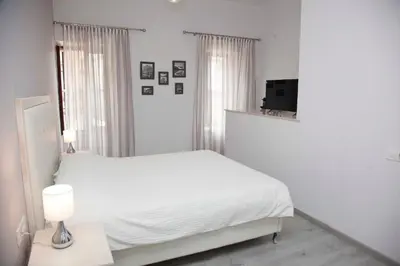 a white bedroom with a bed and a television at Shalom Luxury Rooms Kondilaki in Chania Town