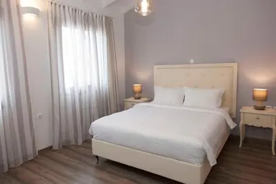 a bedroom with a white bed with two tables and two lamps at Shalom Luxury Rooms Kondilaki in Chania Town