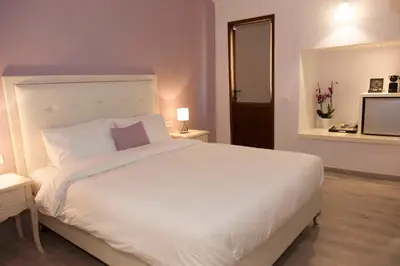 a bedroom with a large white bed and a television at Shalom Luxury Rooms Kondilaki in Chania Town