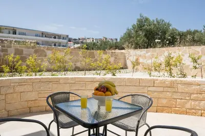 a table with a bowl of fruit and two glasses of orange juice at NEA Dreamy Houses in Agia Marina Nea Kydonias