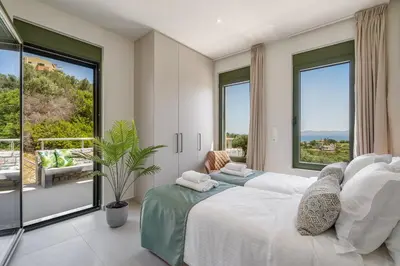 a bedroom with two beds and a large window at Villa Meraki in Stalos