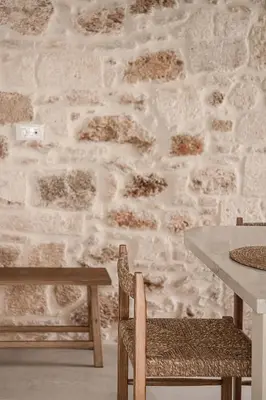 a table and chairs in front of a stone wall at Off Apartments in Chania Town