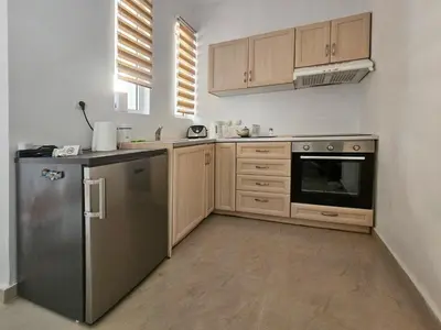 a kitchen with wooden cabinets and a stainless steel refrigerator at Dafne Almyrida Beach Apartment in Almirida