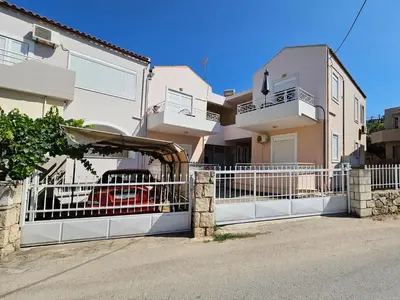 a white fence in front of a house at Dafne Almyrida Beach Apartment in Almirida