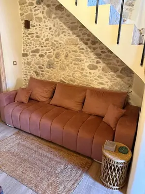a brown couch in a room with a stone wall at Stay near Balos & the seaside in Kaloudhianá