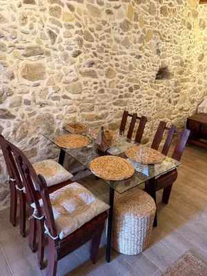 a dining table with chairs and a stone wall at Stay near Balos & the seaside in Kaloudhianá