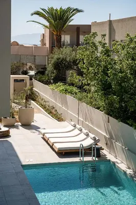 a swimming pool with chaise lounges next to a building at Aurea Beach Villa in Kato Daratso