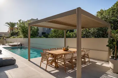 a wooden pergola on a patio with a table and chairs at Aurea Beach Villa in Kato Daratso