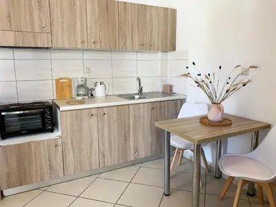 a kitchen with wooden cabinets and a table with a microwave at Platanias Memories Studio 3 in Plataniás
