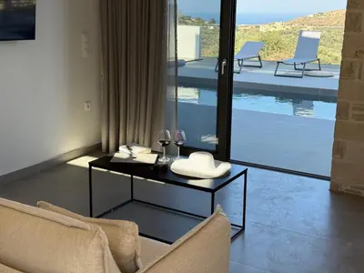 a living room with a table with two wine glasses at Sunrise Village Aptera Private Pool Villa in Beritianá