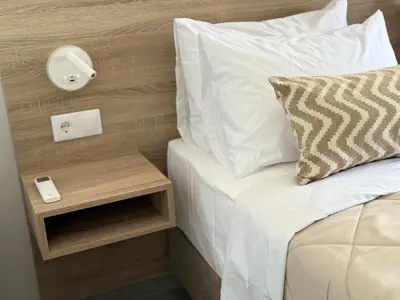 a bed with white sheets and a night stand next to it at Sunrise Village Aptera Private Pool Villa in Beritianá