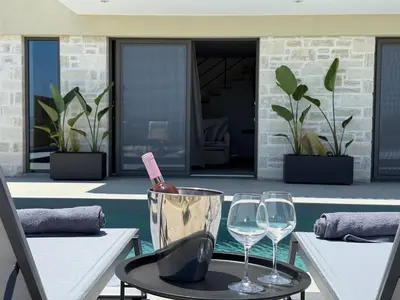 a table with two glasses and a bottle of wine at Sunrise Village Aptera Private Pool Villa in Beritianá