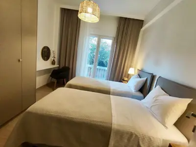 a hotel room with two beds and a window at Kalliso City Apartment near the beach in Chania Town