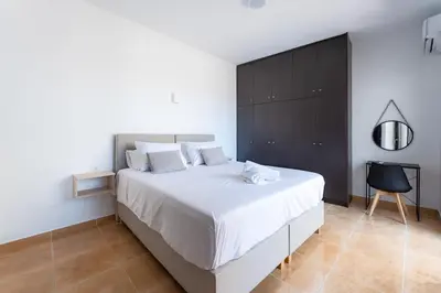 a bedroom with a white bed and a black cabinet at Kalamaki Del Mar in Chania Town