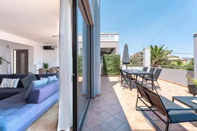 a living room with a blue couch and tables and chairs at Kalamaki Del Mar in Chania Town