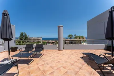 a patio with chairs and umbrellas on a roof at Kalamaki Del Mar in Chania Town