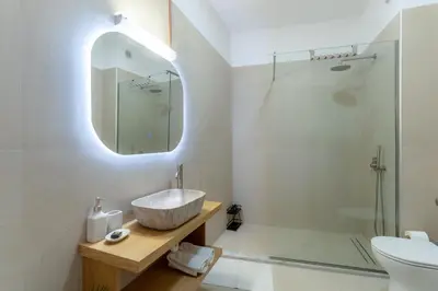 a bathroom with a sink and a toilet and a mirror at Kalamaki Del Mar in Chania Town