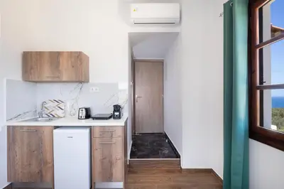 a kitchen with white counters and wooden cabinets at Anastasia Veridian Living in Kalathas