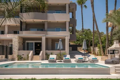 a villa with a swimming pool and two lounge chairs at Kymélia Luxury Residences With Sea View in Galatás