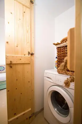 a laundry room with a washing machine and a wooden door at Mera Beachfront House - Falasarna in Falasarna