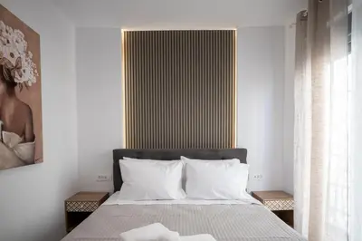 a bedroom with a bed with white sheets and a window at The Cozy Twins in Chania Town