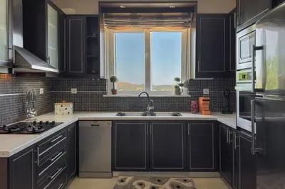 a kitchen with black cabinets and a sink and a window at Kyparisses Villa with Private Pool in Chania Town
