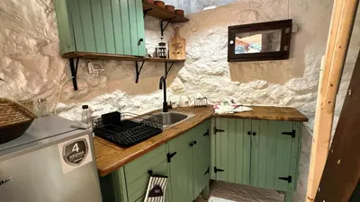 a small kitchen with green cabinets and a sink at The Root House - Crete Stay in Vafés