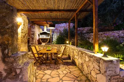 a patio with a table and chairs on a stone wall at Vrisali Traditional Stone Villa in Gerolakkos