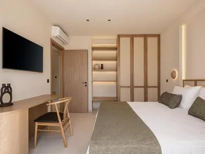 a bedroom with a bed and a desk with a television at Onora Villa - Steps from the Sea by etouri in Nopíyia