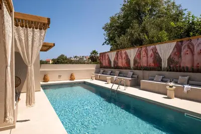 a swimming pool with chairs next to a house at Aladdin Luxury Suites With Shared Pool in Galatás