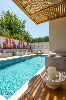 a swimming pool with a table and a candle at Aladdin Luxury Suites With Shared Pool in Galatás