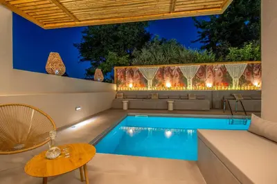 a pool in a backyard with a chair and a table at Aladdin Luxury Suites With Shared Pool in Galatás