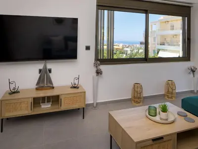 a living room with a tv and a couch and a table at Lum Urban Suites in Chania Town