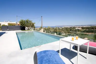 a villa with a swimming pool and a table at Andreas Villa in Kato Daratso