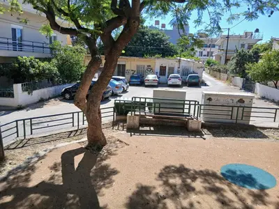 a tree in front of a fence next to a parking lot at Orange Tree in Chania Town