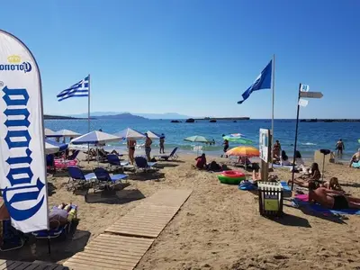 a group of people on a beach with a surfboard at Seafront Apartment in Chania 6 in Chania Town