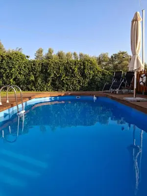 a blue swimming pool with two chairs and an umbrella at Terra Solaris Guesthouse in Kissamos