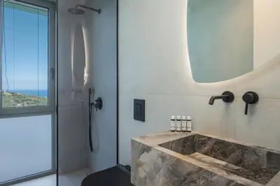 a bathroom with a sink and a shower with a mirror at Sky Sea View Villas in Chania Town