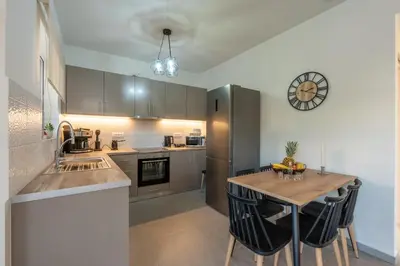 a kitchen with a table and a clock on the wall at Heart Of Galatas Apartments Holidays In crete in Galatás