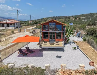a small house with an orange umbrella and a chair at Casa Luma near Loutraki beach in Chania