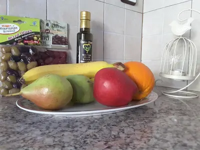 a plate of fruit on a counter with a bottle of wine at Panorama Apartment in Kefálion
