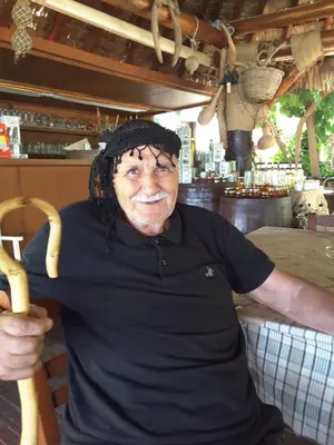 an older man is smiling while holding a baseball bat at Panorama Apartment in Kefálion