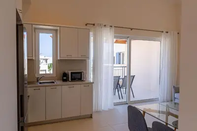 a kitchen with white cabinets and a table and a balcony at Phaedrus Living Seaside Thalassa Cretan 201 in Módhion